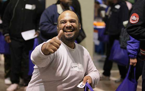 Man with thumbs up getting help to get off the streets