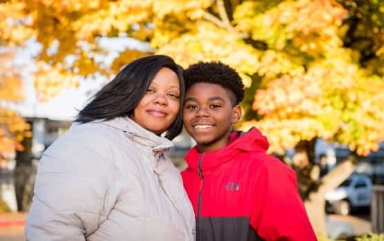 Woman and son smile near trees with bright yellow fall leaves.Thanks to United Way and partners, Aeshia and her son found housing in Seattle after being homeless.