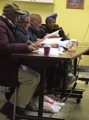 image of four Ethiopian adults sitting at a table, concentrating on packets of paper