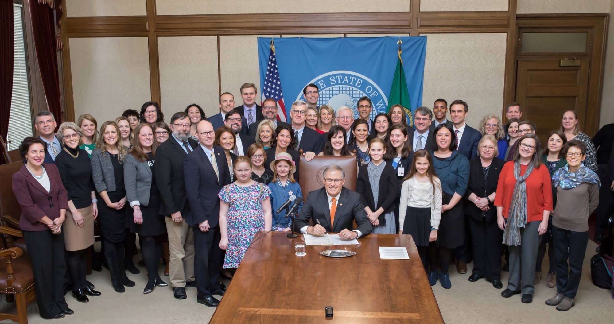 Image of Governor Inslee surrounded by United Way advocates, signing Second Engrossed Substitute House Bill No. 1508,