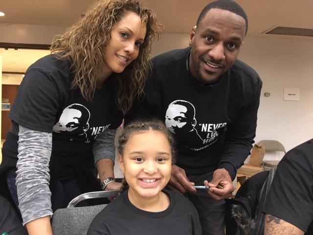 A mother, father and daughter smiling at camera at a family volunteering event.