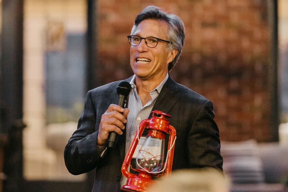 Dan Bretter on stage holding his award while giving his acceptance speech.