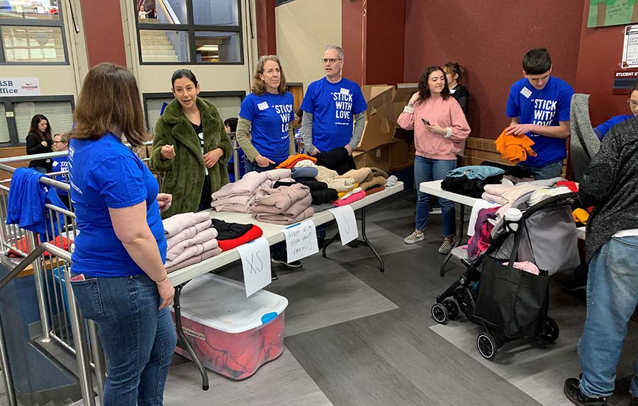 Several people standing behind a table of clothing