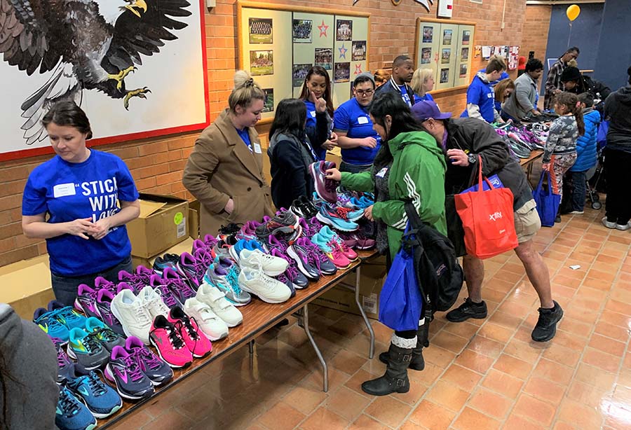 People looking at shoes while volunteers stand behind a table