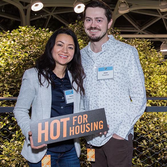 Two champion donors pose for photo holding a sign that reads "hot for housing"