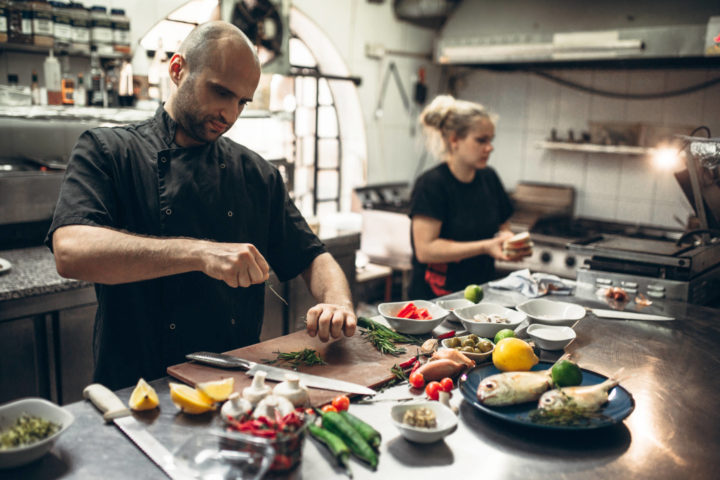 Two cooks preparing food in a commercial kitchen.