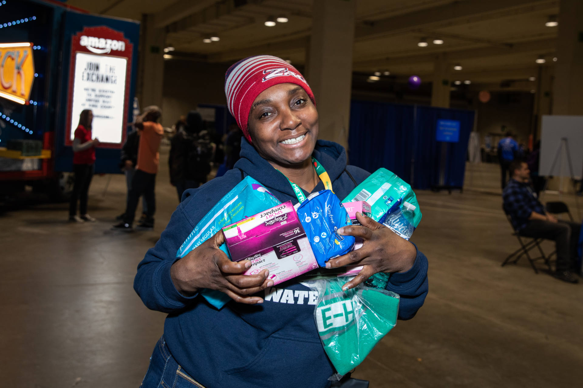 A Guest at the 2019 Community Resource Exchange stands smiling at camera holding supplies given at the event.