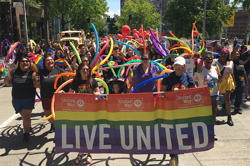 United Way of King County employees marching in the 2019 Seattle Pride parade. The people in the front are caring a large rainbow colored banner that says 