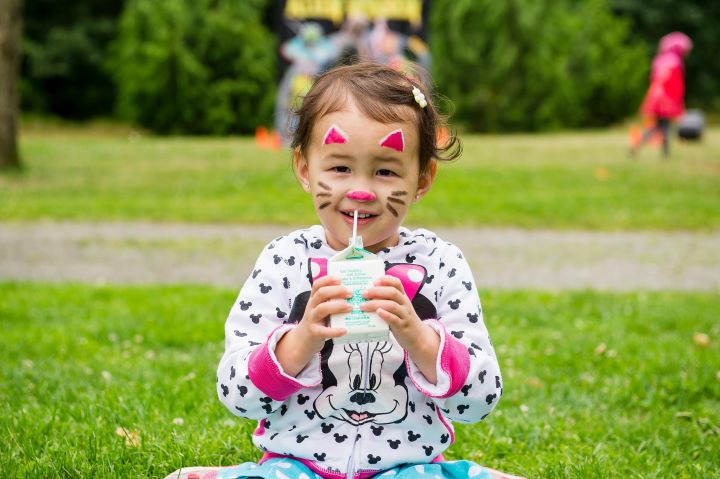 A young person with a painted face holding a child's drinking cup.