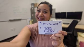 A woman holding a card with the number of diapers she has collected.