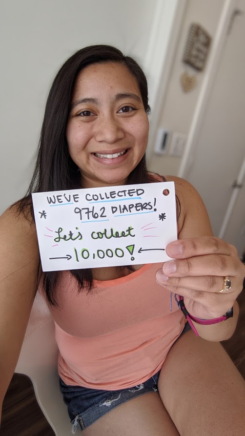 A woman holding a card with the number of diapers she has collected.