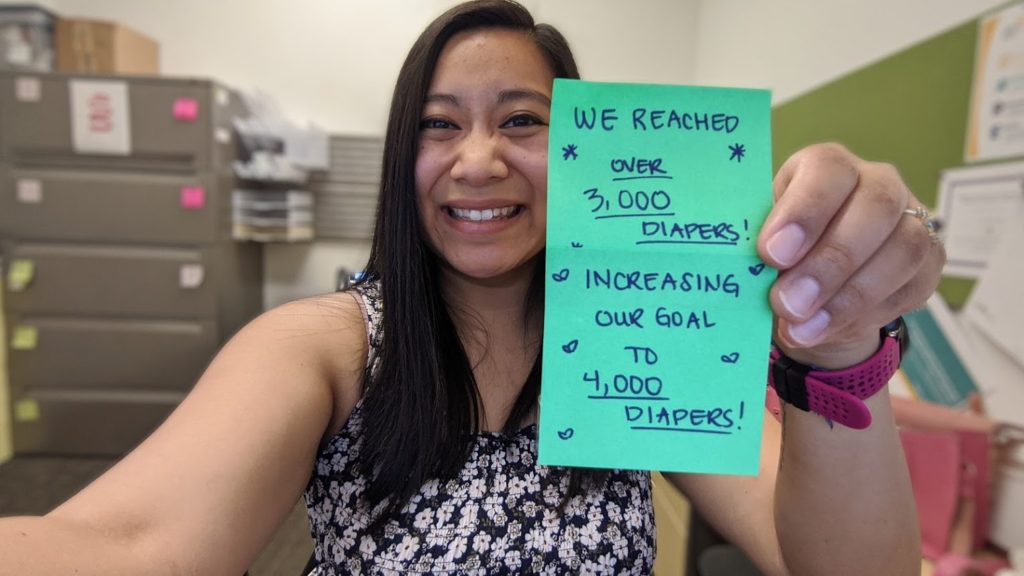 A woman holding a card with the number of diapers she has collected.