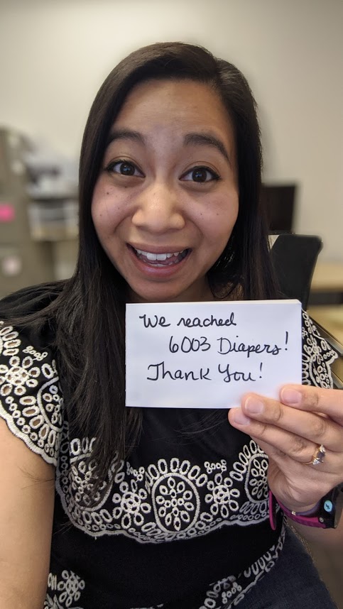 A woman holding a card with the number of diapers she has collected.