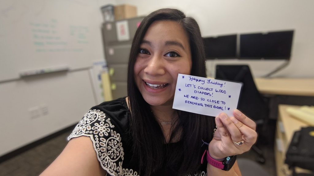 A woman holding a card with the number of diapers she has collected.