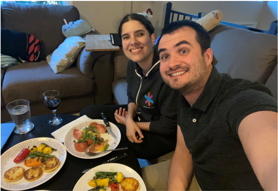 Philip and Julianna take selfie infront of their plates of food that they made at home while watching the Change makers celebration cooking demo with Ethan Stowell