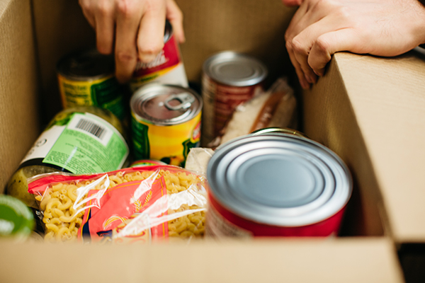 close up of a person organizing a box of canned foods