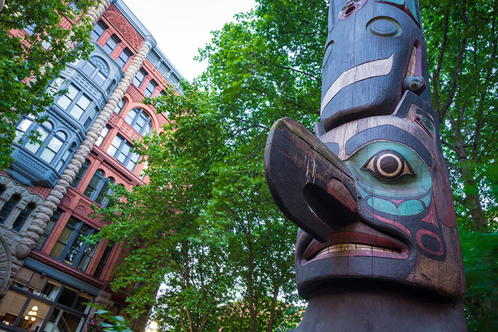 An Indigenous Totem Pole with Seattle residential building in the background