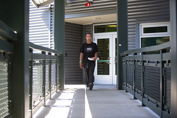 Student holding a book walks in an outdoor hallway at school