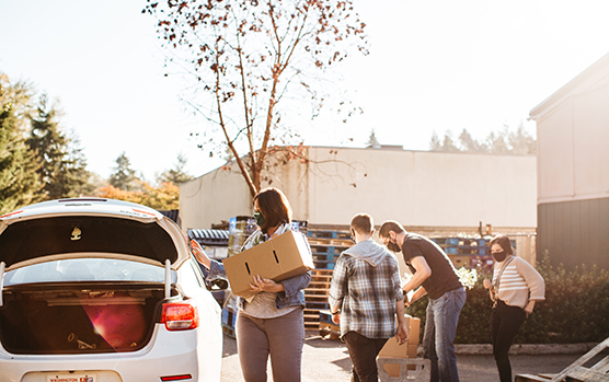 A group of people wearing masks helping to load food boxes onto a car for delivery