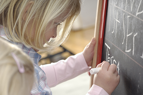 A young child writes on a chalkboard.