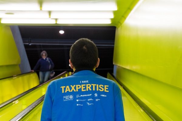 Photo of the back of a person who is wearing a blue shirt that reads "Taxpertise"