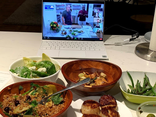 Meal kits assembled sitting in front of laptop with video of virtual chefs table.