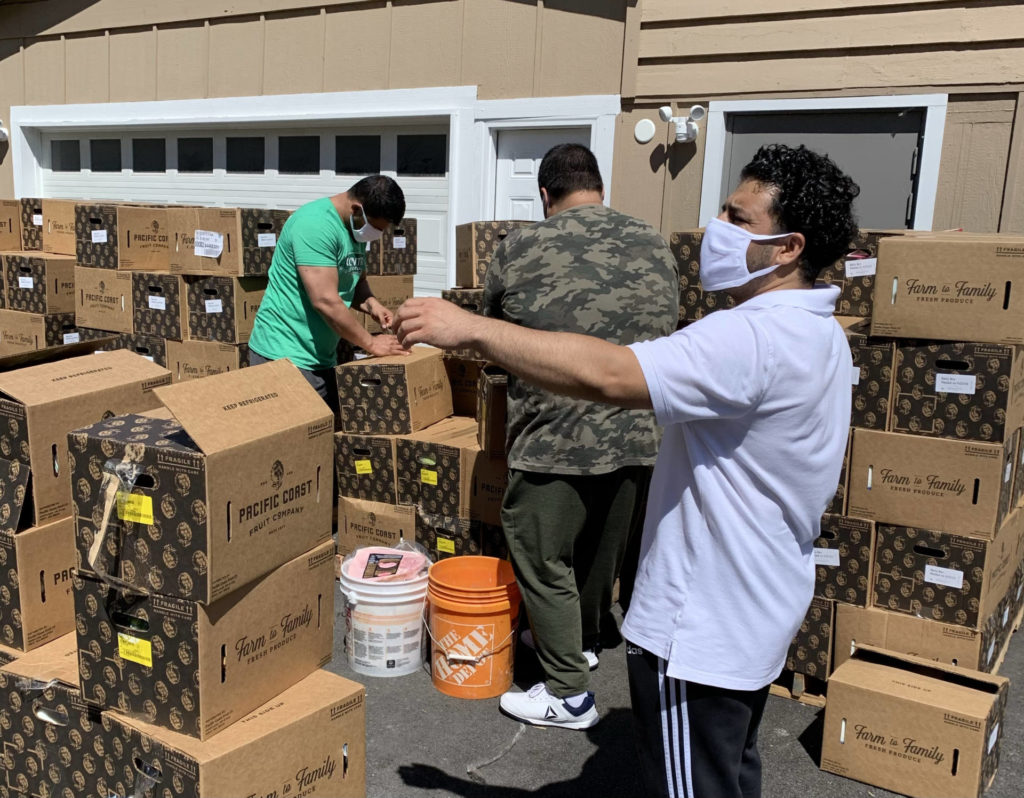 Three people working with boxes of food.