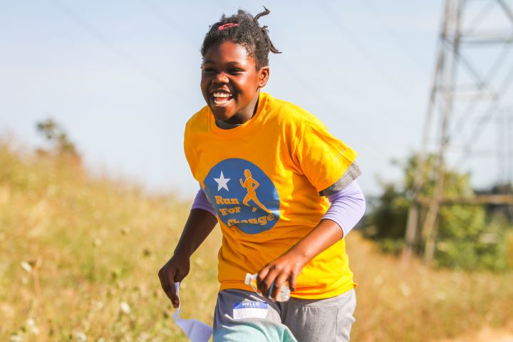 A girl running outside smiling on a sunny day.