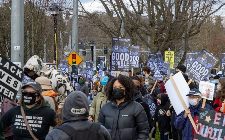 Several dozen people at a Martin Luther King Day march with signs of support for Black people.