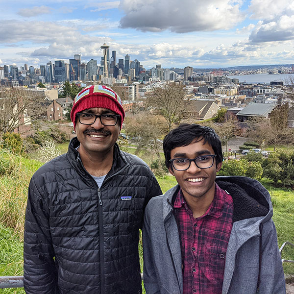 Lak Lakshmanan and his son stand before the city of Seattle skyline