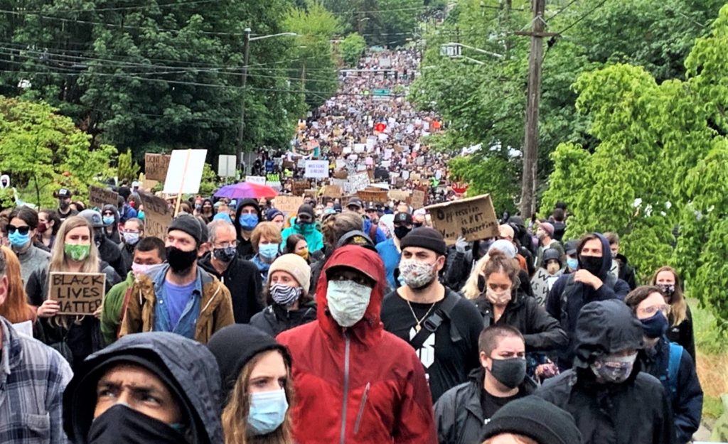 Thousands of peaceful protesters wearing masks on a Seattle street.