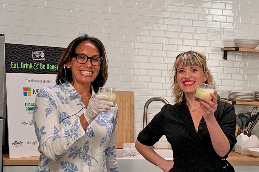 Owner of Marination, Kamala Saxton,  and radio personality Brooke Fox, hold up cocktails in a kitchen studio at one of the virtual Be Generous events.