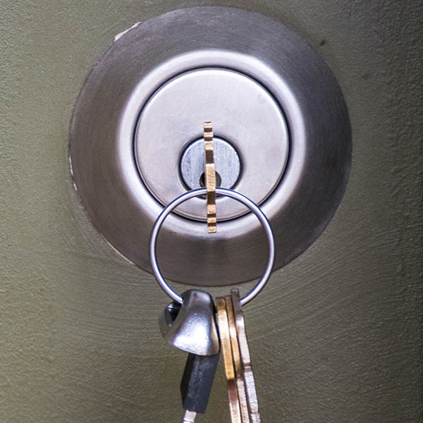 close up of an apartment door lock with a set of keys hanging from the key hole