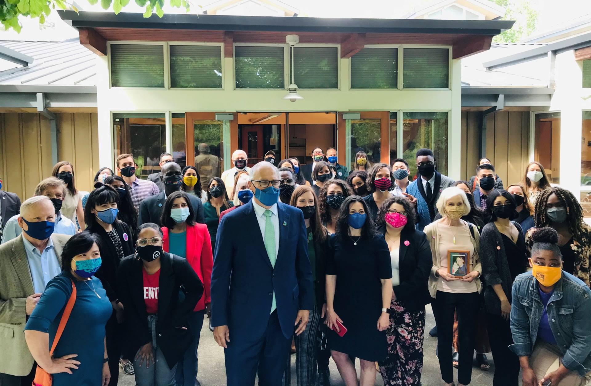 Governor Inslee standing with a group of advocates and legislators. Everyone is wearing facial covers.