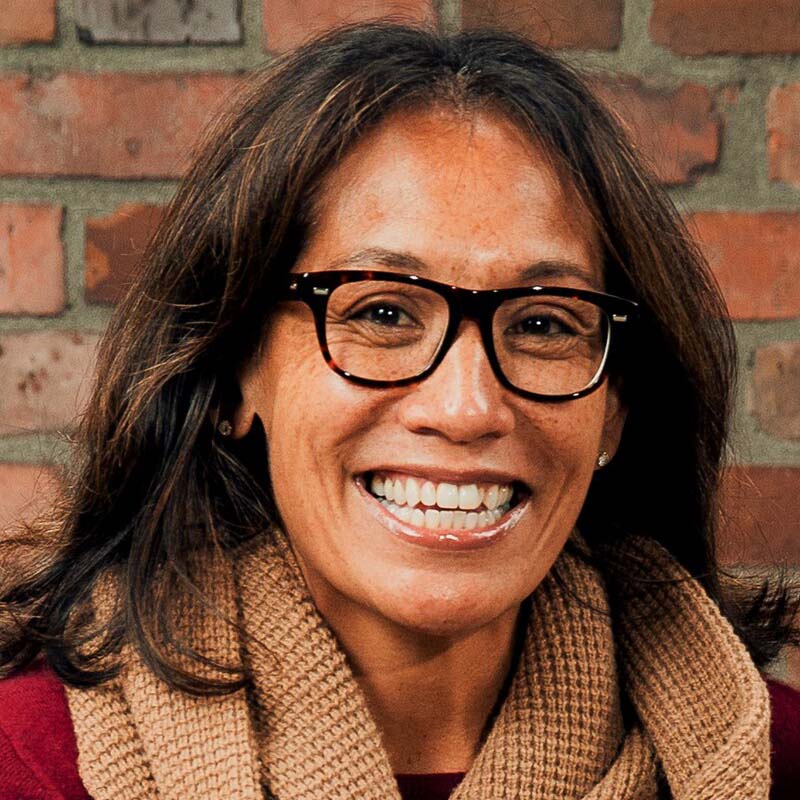 professional headshot of Kamala Saxton, who is wearing glasses, a beige scarf and red blouse