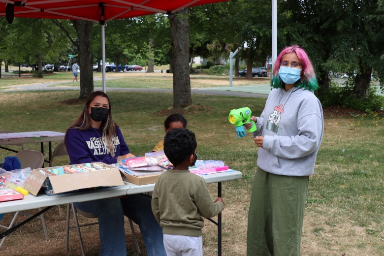 Two AmeriCorps members with two children at a Free Summer Meals site