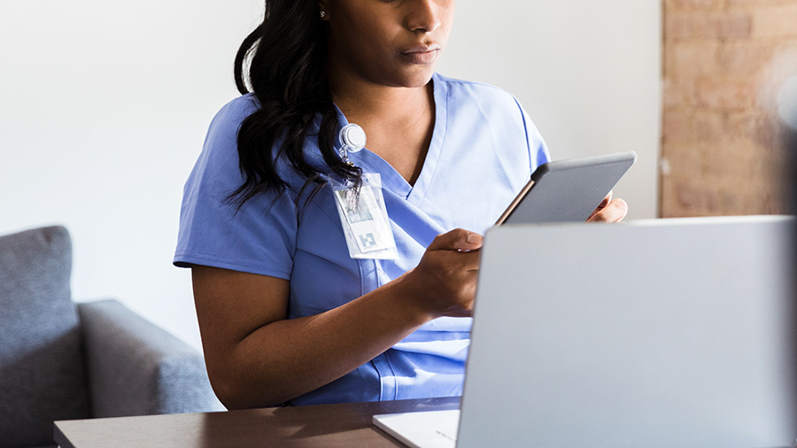 Nurse looking at a chart in front of a laptop