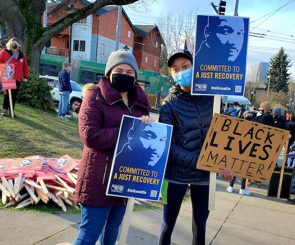 Two volunteers holding a rally sign at MLK Day Rally 2022