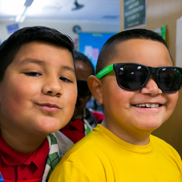 Two young children, one wearing dark sunglasses