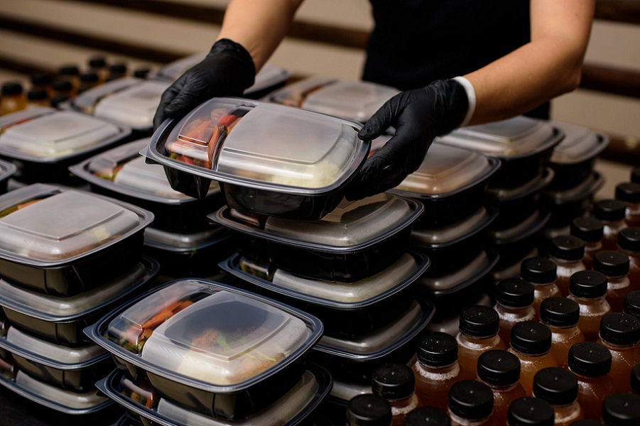 Lunch boxes and drinks with a set of black gloved hands holding one of the lunch boxes.