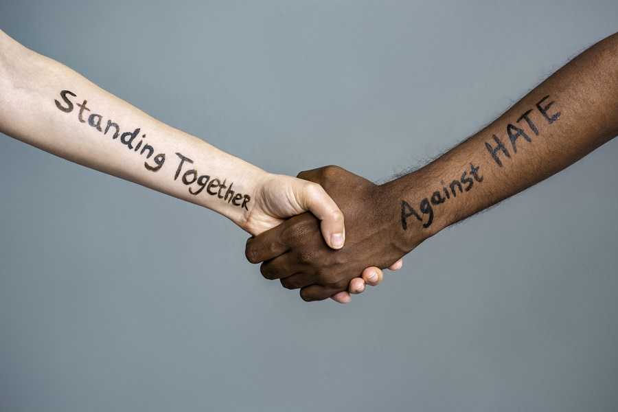 Handshake between black and white human woman and male hands with the message text Standing Together against HATE. Concept of protest protest against racism and police brutality.