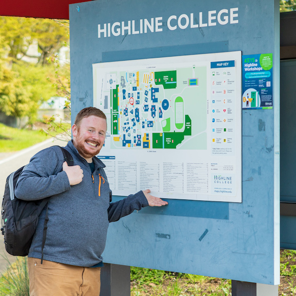 College student standing in front of college map smiling