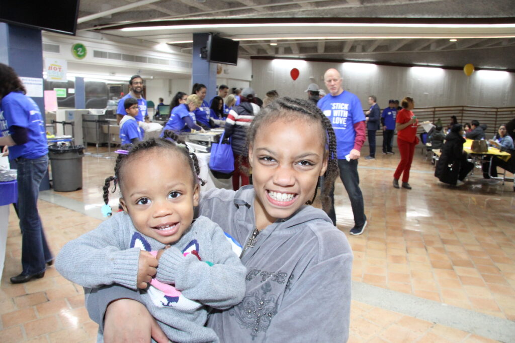 Two kids smiling one holding the other at a resource exchange