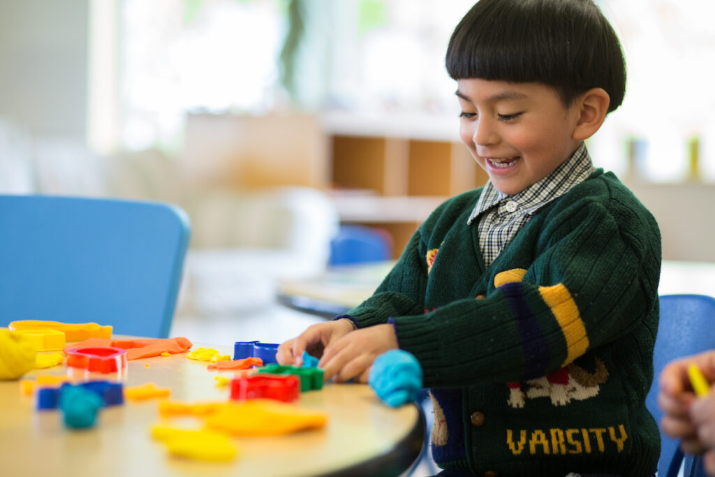 Child playing with blocks at a table and smiling