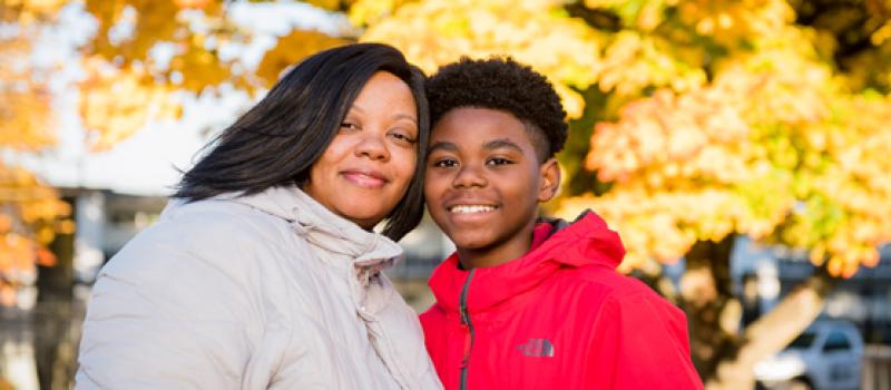 Woman and son smile near trees with bright yellow fall leaves.Thanks to United Way and partners, Aeshia and her son found housing in Seattle after being homeless. Woman and son smile near trees with bright yellow fall leaves.Thanks to United Way and partners, Aeshia and her son found housing in Seattle after being homeless.